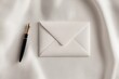© anzodesign - Elegant white envelope and fountain pen on a soft fabric background in a minimalist setting