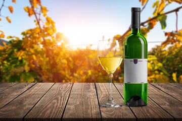 Wall Mural - A glass of wine on a table at vineyard background