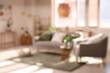 © Pixel-Shot - Blurred view of light living room with grey sofa, armchair and window