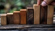 © George Louris  🜲 - A hand adjusting wooden blocks in an increasing height sequence, symbolizing growth and progress in business or learning.