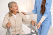 © New Africa - Nurse helping senior woman with walking frame in clinic