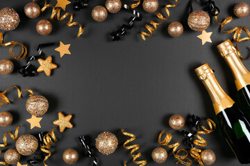 Wall Mural - New Years Eve frame of gold and black decorations, streamers and champagne. Top down view over a black background.