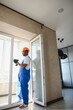 © Serhii - Young African Repairman In Overalls Installing Window