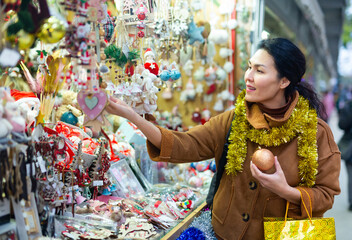 Positive female in tinsel on Christmas fair decoration on holiday