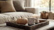 © Poomtan - A coffee table in a living room with a rustic tray holding a candle, a small pumpkin, and a mug of hot chocolate, with a sofa in warm, neutral tones in the background