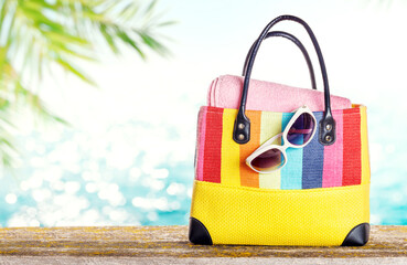 Poster - A beach bag with towels and sunglasses placed on a table