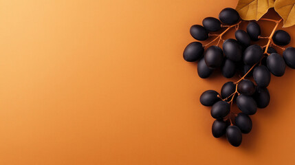 Wall Mural - Cluster of ripe black grapes with stems and leaves on an orange background with ample copy space.