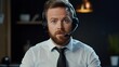 © Oulaphone - A serious-looking man with a beard wearing a headset speaks into a microphone in a dimly lit office environment.