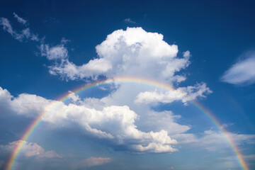 Wall Mural - Cloudy blue sky with a multi-colored rainbow passing through it.