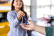 © Graphicroyalty - Dealer handing car key to businessman with electric SUV in background inside car dealership, symbolizing sustainable transportation, vehicle purchase, and business success.