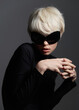 © SHOTPRIME STUDIO - Elegant young woman with short white hair wearing oversized black sunglasses. Posing dramatically against a dark background, showcasing modern fashion and style.