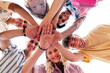 © Westend61 - Multi-ethnic group of young friends stacking hands looking down at camera