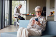 © Westend61 - Senior woman sitting on couch at home using mobile phone