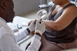 © Seventyfour - Over shoulder shot of African American doctor examining skin of patient with magnifying glass during consultation in dermatology clinic copy space