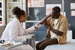 © Seventyfour - Side view portrait of African American woman as female dermatologist consulting patient in clinic and examining skin