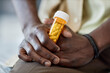 © Seventyfour - Closeup of unrecognizable African American man holding bottle of pills struggling with mental health issues and taking antidepressants copy space
