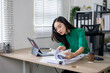© Wasana - Young asian businesswoman working with documents and digital tablet at the office