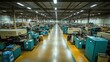 © AFFANYUDA - An empty factory floor with rows of blue industrial machines in a manufacturing plant.