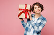 © ViDi Studio - Young woman she wear blue shirt white t-shirt casual clothes hold in hand present box with gift ribbon bow look aside isolated on plain pastel light pink background studio portrait. Lifestyle concept.