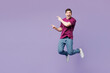 © ViDi Studio - Full body young Caucasian man wear violet t-shirt casual clothes jump high point index finger aside on area mock up isolated on plain pastel light purple background studio portrait. Lifestyle concept.