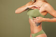 © ViDi Studio - Close up cropped side view young lady woman with slim skinny body perfect skin she wear top bra lingerie stand put hand on breast chest isolated on plain green background. Lifestyle diet fit concept.
