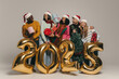 © gstockstudio - Joyful friends holding Christmas ornaments and gift boxes while celebrating 2025 New Year on studio background