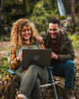 © Miljan Živković - wife hiker work remote on laptop in front waterfall with husband nearby