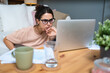 © Srdjan - Smiling young woman working at home. Successful professional occupation female work on laptop computer, e-commerce, online education, internet earnings, plans and side hustle. Calculating, statistics