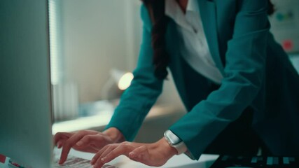 Wall Mural - Young businesswoman in a teal jacket types on a keyboard, showing signs of frustration as work challenges mount and deadlines approach, reflecting stress and pressure in the office