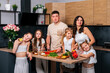 © dvulikaia - Large family - mom, dad, four daughters  together prepare salad for lunch in modern kitchen. Big family together concept.