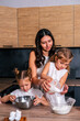 © dvulikaia - A young mother cooks cheeseecake  with her daughters. Mom teaches her daughters to cook.