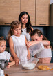 © dvulikaia - A young mother cooks cheeseecake  with her daughters. Mom teaches her daughters to cook.