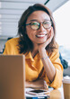 © BullRun - Portrait of Chinese female student smiling at camera during studying day in unoversity classroom, happy hipster girl posing during break from e learning on laptop and exam preparation indoors