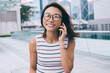© BullRun - Half length portrait of joyful woman in optical glasses smiling at camera during international cell conversation using 4g internet in roaming, happy female tourist phoning via cellphone gadget