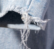 © dvulikaia - Close-up of protruding threads on worn blue jeans