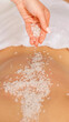 © Prostock-studio - Spa scrub massage. Female hands sprinkle salt on bare back of girl, close up