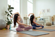 © tonefotografia - Two young  Asian woman friends practicing yoga at home.