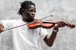 © SOLO PLAYER - Candid of African man model with dreadlocks hairstyle wearing white t-shirt playing violin standing at the background