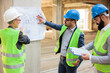© Ivan - Team of successful young architects and business partners during a meeting on a construction site. Looking at architectural drawings and blueprints.