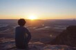 © Iftikhar alam - A person sitting on a rock, observing the setting sun over the desert, Watching the sun rise over a breathtaking desert landscape