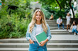 © Erik González - A young woman wearing a blue jacket and holding a green book