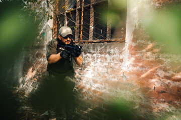 Wall Mural - Soldier aiming with assault rifle near abandoned building