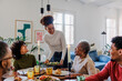 © BONNINSTUDIO/Stocksy - Happy family enjoying food and smiling during lunch at home