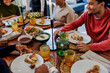 © BONNINSTUDIO/Stocksy - Happy family enjoying thanksgiving dinner together around table