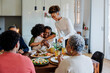 © BONNINSTUDIO/Stocksy - Happy family sharing christmas meal celebrating with hugs and love