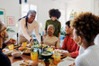 © BONNINSTUDIO/Stocksy - Happy family is sitting at the table and having dinner together