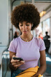 © Ezequiel Giménez/Stocksy - Woman Texting on Train with Earbuds
