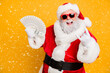 © deagreez - X-mas lottery win credit bank present for noel. Funky crazy hipster white bearded santa claus hold money fan show horned symbol enjoy deposit gift wear red hat isolated yellow color background