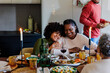 © BONNINSTUDIO/Stocksy - Family enjoying christmas meal together around a table