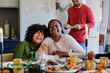 © BONNINSTUDIO/Stocksy - Family laughing together during christmas dinner at home